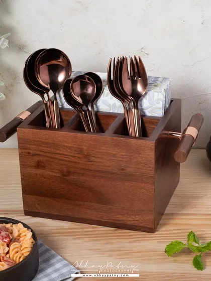 This image showcases a wooden cutlery holder in a dining context. The background props like the pasta bowl and plant help customers visualize how this stylish organizer would look on their table.