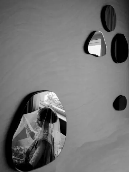 A creative black and white shot of the bride's reflection in a series of decorative mirrors.