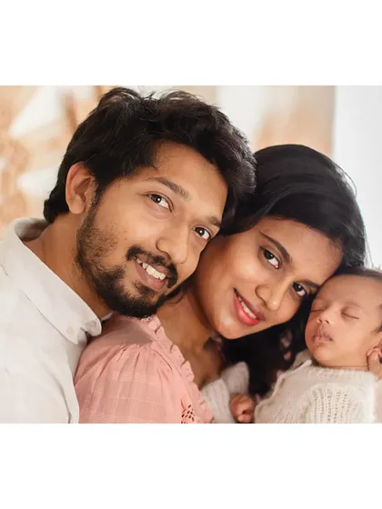 A happy family portrait, with the newborn sleeping peacefully in their parents' arms.
