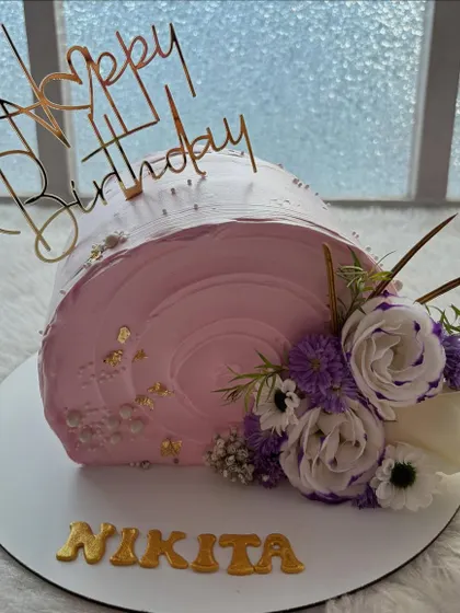 A pink top-forward cake with a beautiful arrangement of fresh flowers. This unique cake shape always makes a statement.