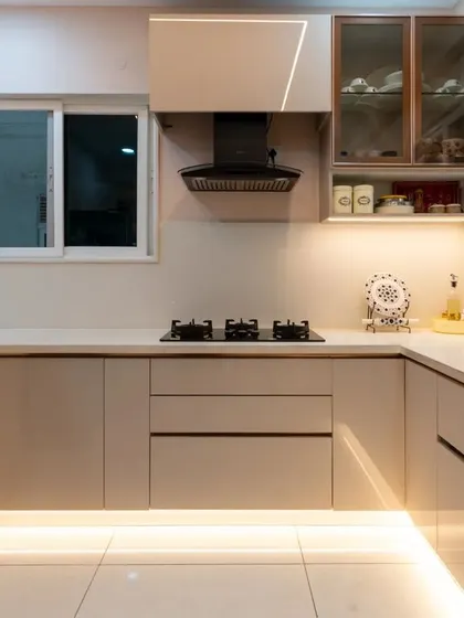 A wide view of the beige U-shaped kitchen, showing the efficient work triangle and the warm glow from the profile lighting at the base of the cabinets.