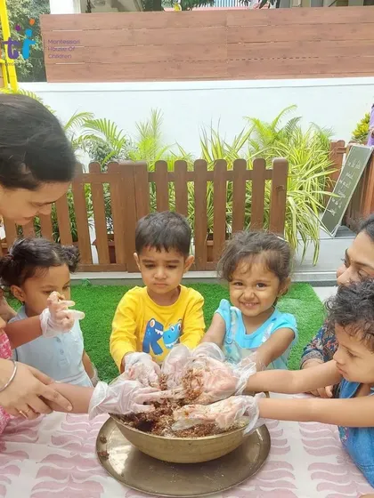 Toddlers get their hands into the mixing bowl with the help of their teachers. These sensory experiences are crucial for early childhood development and learning.