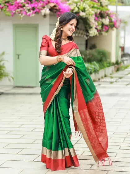 Bright and cheerful outdoor portraits of an actress in a vibrant green and red saree. The natural lighting and blooming flowers in the background complement her radiant smile.