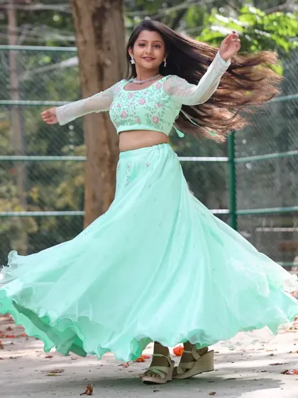 The client looks joyful and carefree in her custom lehenga. The embroidered crop top and flowing skirt are perfect for outdoor events.