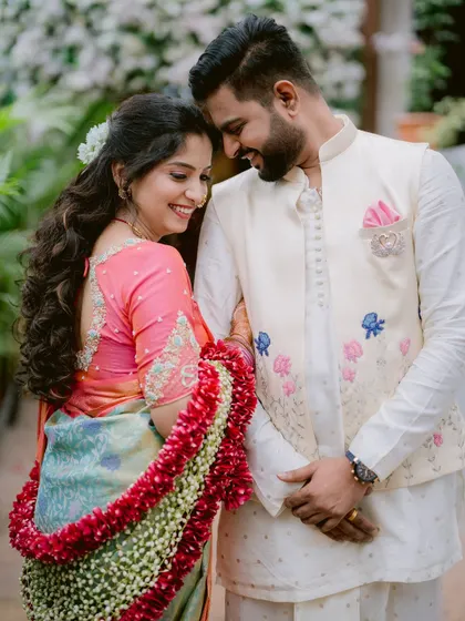 A sweet, candid moment between Gayatri and Saurabh during their engagement, framed by lush greenery.