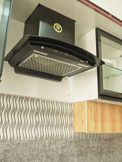 This kitchen features a textured, wavy-patterned grey tile backsplash that adds subtle movement and interest. The design is paired with white and light wood cabinets for a soft, modern look.