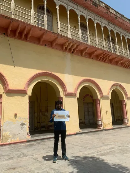 A team member holding up a plan against the backdrop of the haveli's grand facade, symbolizing the beginning of a meticulously planned restoration journey.