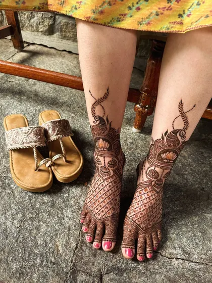 This foot design features peacocks and lotuses with delicate jaali netting, perfectly matching the bride's hand designs.