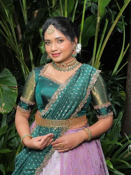 A beautiful portrait of a client in a green and pink langa voni, showcasing the rich colors and traditional jewelry.