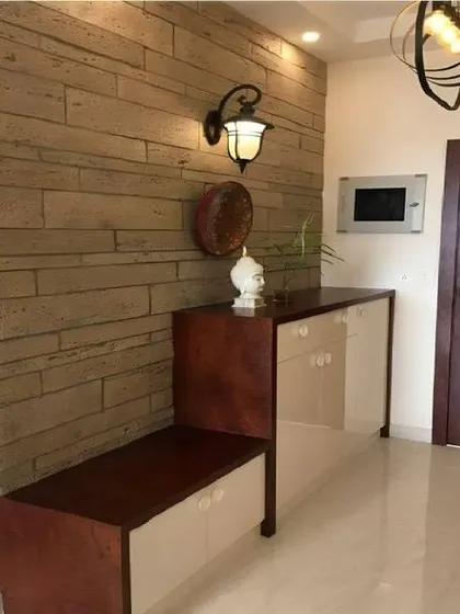 A rustic-chic entryway with a wood-paneled accent wall and a simple bench with shoe storage. The classic wall lamp adds a touch of vintage charm.