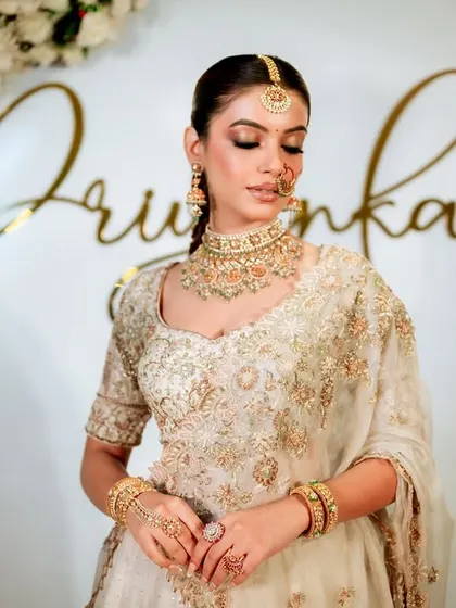 A full shot of the bride against a backdrop with her name. The makeup is elegant and sophisticated, perfect for a modern bride who appreciates fine details.