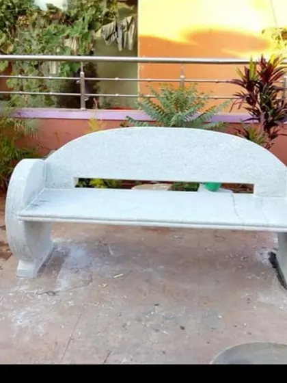 A solid stone bench with a modern design, featuring a cutout in the backrest. These benches are extremely durable and require no maintenance.