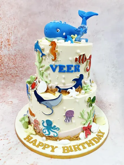 We dive deep into an underwater adventure with this two-tiered sea creatures cake. A magnificent blue whale tops the cake, which is covered in a variety of ocean friends like dolphins, stingrays, and octopuses, creating a vibrant aquatic world.