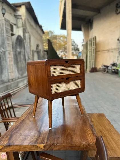 A close-up of the nightstand, focusing on the cane weaving and the integrated drawer pulls.