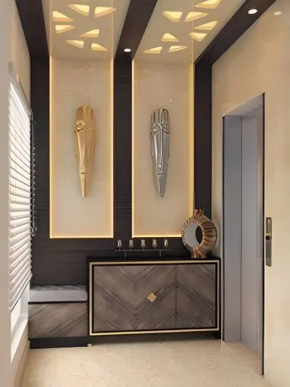 A dramatic foyer design with niche lighting highlighting two tribal masks. The dark wood console and false ceiling with geometric cutouts add to the sophisticated atmosphere.