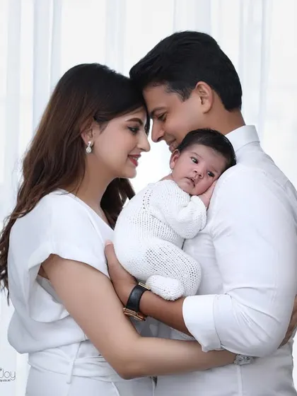An intimate family moment, with parents touching foreheads as they hold their newborn. The soft window light creates a gentle and loving mood for this in-home portrait.