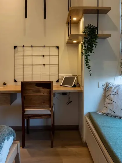 A multifunctional bedroom corner with a floating study desk and open shelving, perfect for a compact space.