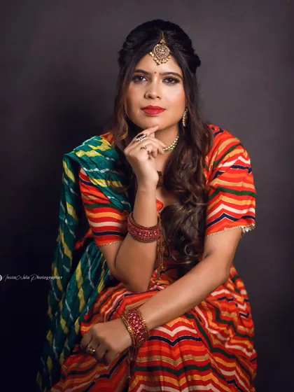 This pose highlights the beautiful bandhani dupatta and traditional jewelry. The makeup ties it all together with a classic red lip and defined eyes, creating a look that is perfect for any festive celebration.