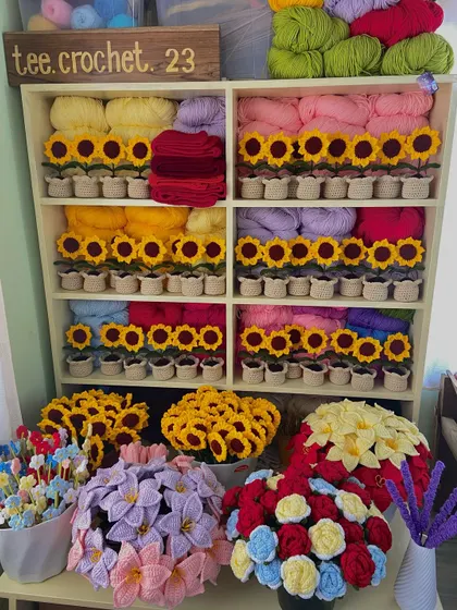 My favorite corner of the workshop, featuring shelves neatly organized with potted sunflowers and various yarn colors.