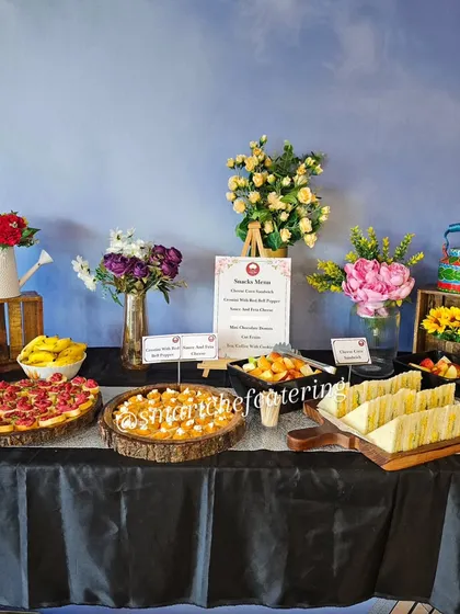 A beautiful spread for a corporate office inauguration. The table is elegantly decorated and features a variety of snacks including crostini, sandwiches, and fresh fruit.