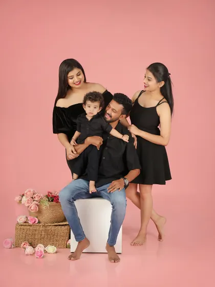 The smallest moments can be the most beautiful. This lovely family portrait against a soft pink background is full of warmth and affection.