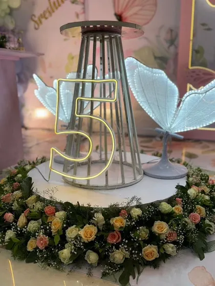 A unique centerpiece featuring a neon number "5" inside a cage, surrounded by a wreath of fresh flowers.