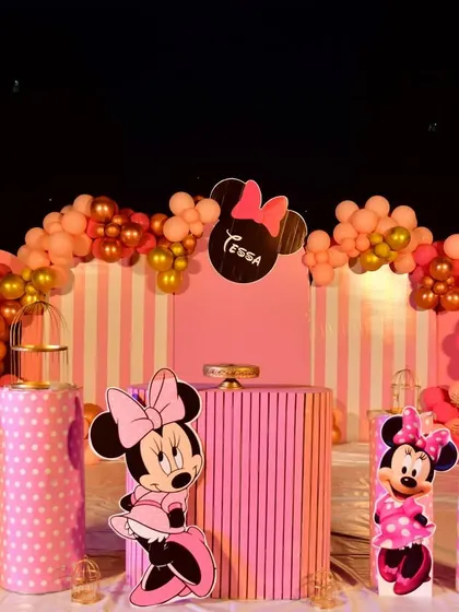 The full view of the Minnie Mouse party, showing the striped backdrop and balloon arch.