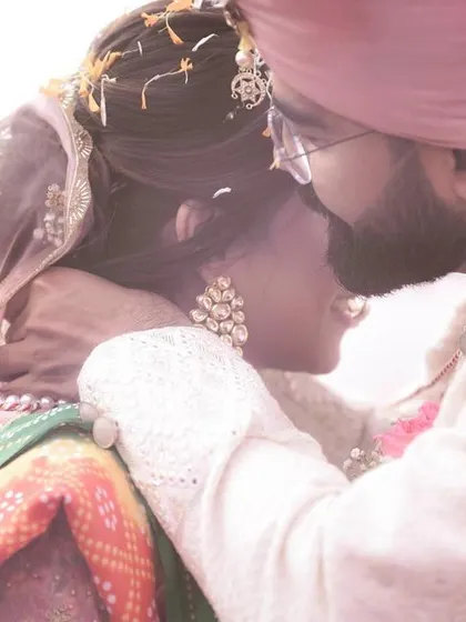An intimate and emotional moment during the wedding ceremony. The groom gently kisses the bride's head, a candid gesture of love and protection captured in a beautifully soft-focused shot.