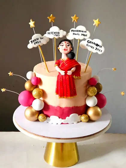 For a mother's 65th birthday, I created this elegant cake featuring a custom figurine in a red saree. The clouds above her mark key milestones in her life, making it a deeply personal and celebratory piece.
