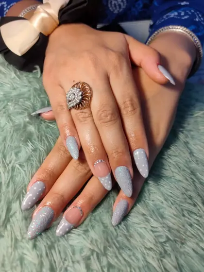 A simple yet stunning design featuring stiletto nails with a textured, light grey glitter polish. The negative space and rhinestone details on the accent nails add a modern touch.