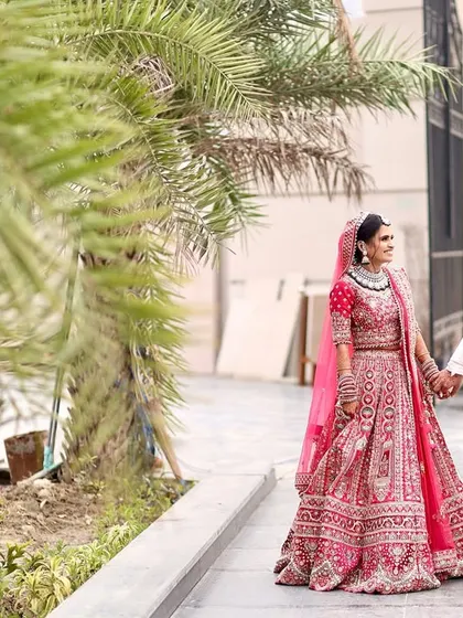 An outdoor wedding portrait of the couple walking together, framed by palm trees, creating a relaxed and natural feel for their wedding album.