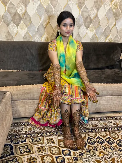 A full-length photo of a happy bride, showing her complete hand and leg mehndi.