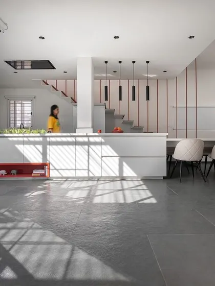 The open-plan kitchen and dining area is designed for connection. The long dining table extends from the kitchen island, creating a central hub for cooking, eating, and socializing, all while being bathed in natural light from the adjacent courtyard.
