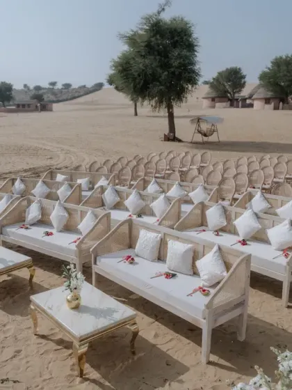 The elegant guest seating arrangement for the sand dune wedding, with white cushioned benches and tables.