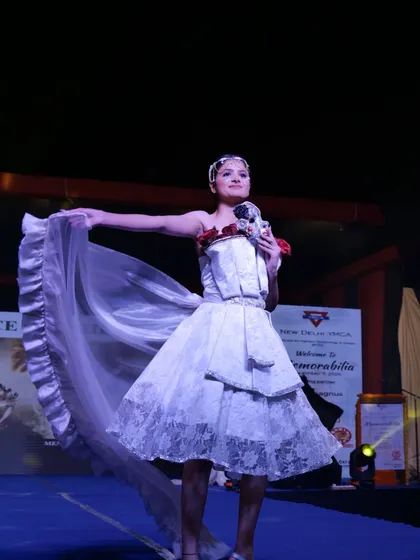 A model displays a deconstructed white dress with a ruffled train, showcasing creative pattern-making.