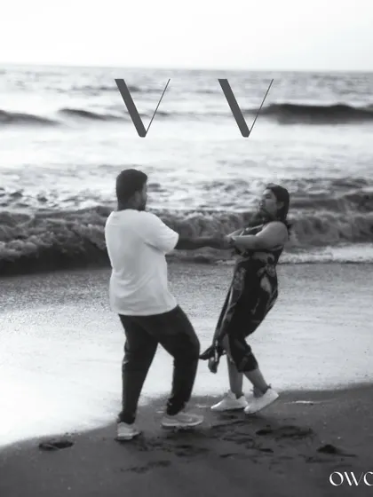 A fun and candid black and white photo of the couple dancing on the beach, showcasing their playful side.
