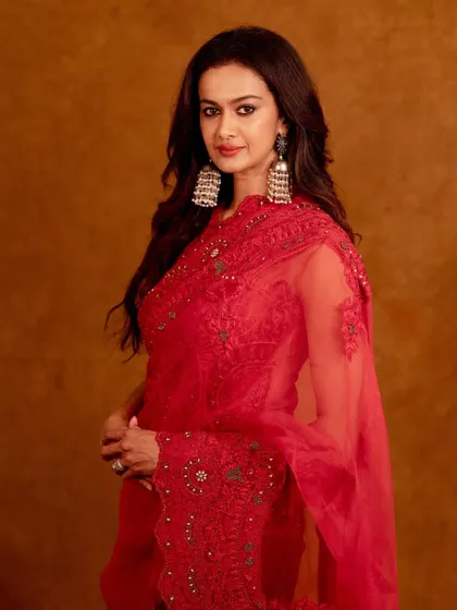 A classic three-quarter portrait in a stunning red saree. The warm studio lighting enhances the rich color and intricate embroidery, creating a sophisticated and timeless image.