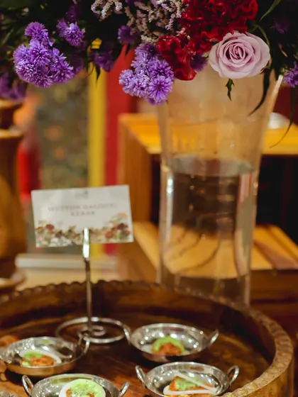 Our Mutton Galouti Kebabs are presented in elegant mini steel bowls, garnished with mint chutney. This setup was part of a grand inauguration, complemented by beautiful floral arrangements.