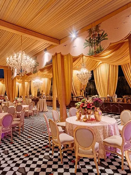 Another view of the dining area, showing the elegant tables set under a canopy of golden fabric and crystal chandeliers.