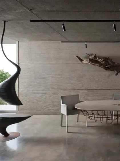 A detail from our studio's meeting area, showcasing custom-designed sculptural furniture against a backdrop of board-formed concrete. The hanging seat and driftwood wall art are functional sculptures that reflect our belief that every element in a space should be a piece of art.