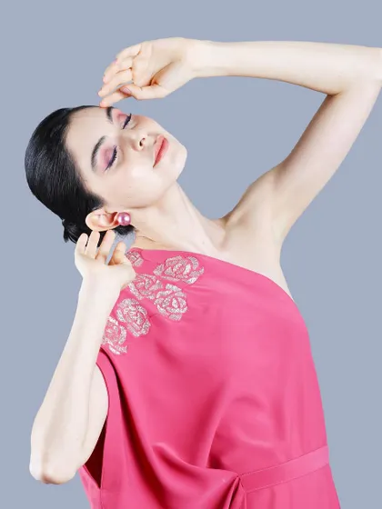 An expressive, high-fashion pose captures the model's profile and the elegant silhouette of the pink gown, ideal for a designer campaign.