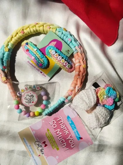 A personalized hamper for a girl named Zainab. This set includes custom name clips, a beaded bracelet, a braided headband, and crochet hair ties.