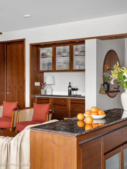 In our 'Gulmohar' project, this niche was transformed into a versatile bar and crockery space. The unit combines veneer, fluted glass, louvered shutters, and a marble buffet top for a vintage feel.