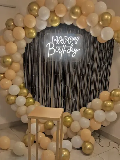 A close-up of the elegant birthday backdrop with a gold, cream, and white balloon garland. The setup is perfect for creating a stylish photo corner at any party.
