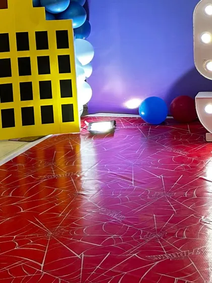 The custom spiderweb floor mat and city building prop used in a Spiderman party setup. I focus on every detail, from the backdrop to the floor.