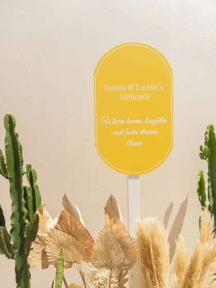 A simple and elegant welcome sign for the Mehendi, surrounded by dried palms and cacti, setting a chic and modern tone.