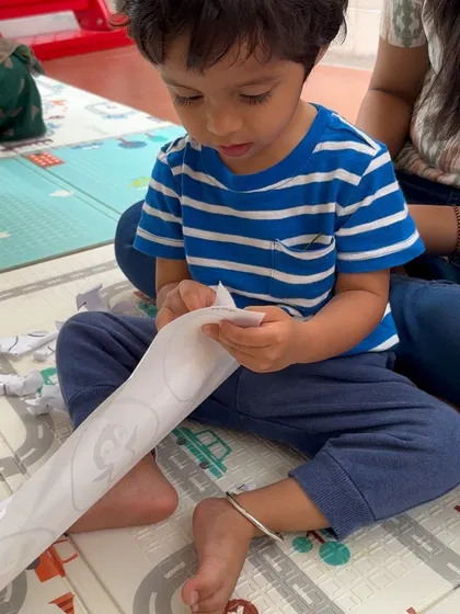 This little one is focused on a fine motor activity. Tearing paper to "hatch" baby animals from their eggs is a fun way to build hand strength while learning about the animal life cycle.