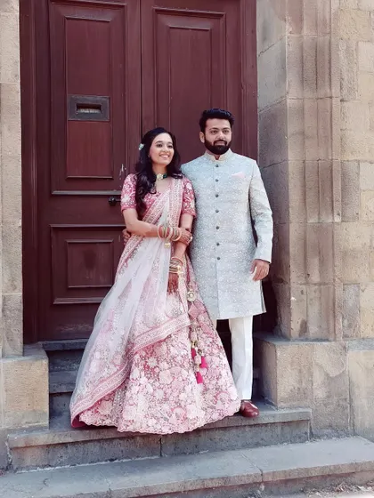 A perfect pair. The bride's soft pink look beautifully complements the groom's elegant attire, creating a timeless wedding portrait.