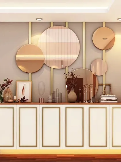 A chic crockery unit featuring a white cabinet with gold inlay details. The wall is adorned with a collection of round, rose-gold mirrors, turning a simple storage piece into a decorative art installation.