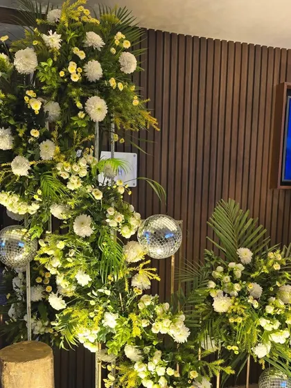A crescent-shaped floral arrangement for a Sangeet ceremony entrance. This piece uses white chrysanthemums and greenery, accented with small disco balls for a touch of modern fun.